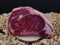 Bistecca di Chianina, un taglio pregiato, pronto per essere cucinato alla tedesca, su un letto di legnetti e noccioli.