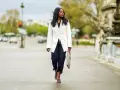 Mujer con estilo **smart casual** camina por la calle con un blazer blanco, jeans oscuros y sandalias de tacón.