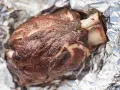 Stinco di maiale succulento, cotto alla perfezione e avvolto in carta stagnola, pronto per essere gustato.