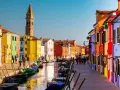 Coloratissima città lagunare con case vivaci, canali e barche ormeggiate.