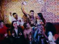 Grupa ludzi świętuje na imprezie w stylu lat 60. z drinkami i zabawnymi okularami.