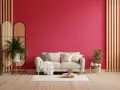 Un divano chiaro su un tappeto bianco, con una parete di un vivace viva magenta. Piante verdi e divisori in rattan completano l'arredamento.