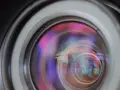 Widok soczewki obiektywu z kolorowymi refleksami, ukazujący aberrację sferyczną.