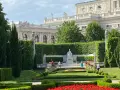 Wiedeń co zobaczyć: piękny ogród z rzeźbą i architekturą w tle.