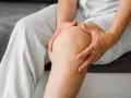Osoba trzyma się za kolano, które może być po naciągniętym przeszczepie ACL.