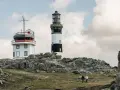 Deux phares se dressent sur une côte rocheuse à Ouessant. Que faire ? Se promener et admirer le paysage, comme ces deux randonneurs.