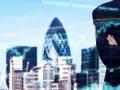 Uomo d'affari con braccia conserte, sullo sfondo la skyline di una città con grattacieli e grafici finanziari, simbolo del lavoro in banca.