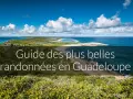 Paysage côtier luxuriant avec la mer bleue et des nuages blancs. Ce guide des plus belles randonnées en Guadeloupe vous invite à explorer ses montagnes verdoyantes.