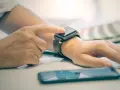 Dłoń z zegarkiem na nadgarstku, palec dotyka ekranu, pokazując jak włączyć bluetooth w smartwatch.