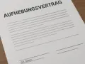 Ein Muster für einen Aufhebungsvertrag, der krankheitsbedingt genutzt werden kann. Das Dokument liegt auf einem Holztisch.