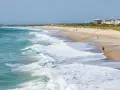 Waves crash on the shore at Wrightsville Beach, where people enjoy a run and a stroll, showcasing some of the relaxing things to do.