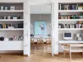 Ampia libreria in cartongesso con libri, computer e decorazioni. Si intravede una sala da pranzo con un quadro astratto.