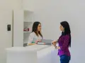 Recepcionista sonríe a paciente, gestionando documentación sanitaria online.