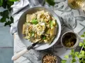 Piatto di pasta ricotta e zucchine, condito con pesto e pinoli, guarnito con basilico fresco.