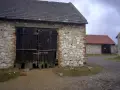 Kamienne stodoły w Żarkach z drewnianymi wrotami, niektóre z czerwonymi dachami.