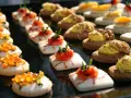 Varietà di finger food da fare in anticipo: tartine con salmone, gamberetti, uova di pesce e noci. Perfetti per ogni occasione.
