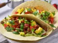 Dwa pyszne, domowe fast foody: tortille z mielonym mięsem, pomidorami, papryką, mango i świeżą kolendrą.