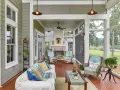 A cozy screened-in patio with a fireplace, wicker chairs, and a sofa, perfect for enjoying the view of the lake.