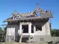 Na dachu domu w budowie, wśród drewnianej konstrukcji, widoczna jest tradycyjna wiecha na dach.
