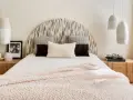 Camera da letto con testiera a semicerchio, cuscini decorativi e coperta rosa. Lampade a sospensione e comodini in legno completano l'arredamento, creando camere aesthetic.