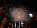 Des mains filment un magnifique feu d'artifice dans le ciel nocturne, capturant la magie de l'instant.
