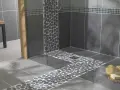 Carrelage moderne avec un chemin de galets sur le receveur de douche, créant une ambiance zen.