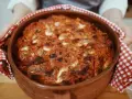 Un invitante pasta al forno ricetta della nonna, appena sfornata in una terracotta, con crosticina dorata e ripieno filante.