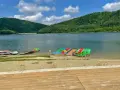 Kolorowe rowerki wodne i kajaki czekają na plaży nad górskim jeziorem.