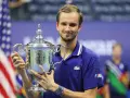 Daniil Medvedev, sonriendo, sostiene el trofeo del US Open, un logro que lo consolida entre los grandes de los medvedev grand slams.