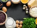 Vielfalt an Lebensmitteln mit Calcium: Milch, Käse, Quark, Eier, Bohnen, Datteln, Nüsse, Orangen und Petersilie.