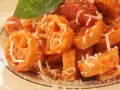 Pasta con ruote e rigatoni conditi con una ricca salsa di pomodoro Bimby, spolverata di parmigiano e guarnita con una foglia di basilico.
