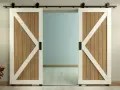 Two white-trimmed, wooden barn doors with black hardware slide open on a black track, showcasing a room beyond. This image illustrates how to install barn door hardware.