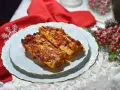 Due cannelloni di carne fumanti, ricoperti di sugo rosso e formaggio filante, serviti su un piatto bianco con bordo dorato, pronti per essere gustati.