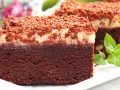 Pyszny torcik brownie z kremową warstwą i posypką czekoladową, ozdobiony listkami mięty.