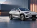 Srebrny SUV BYD Seal U stoi obok ładowarki na tle nowoczesnego budynku.