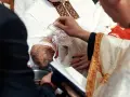 Ceremonia chrztu dziecka. Duchowny polewa główkę niemowlęcia wodą święconą. Warto wiedzieć, ile kosztuje chrzest.