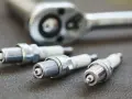 Three spark plugs and a ratchet are laid out, ready for a tune-up. The image highlights the importance of knowing the correct spark plug socket size for the job.