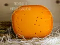 Un trozo de queso Mimolette, de color naranja intenso y con pequeños agujeros, descansa sobre paja. ¡Un queso mimolette peligroso por lo delicioso!