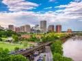 A scenic view of Richmond, VA, showcasing the city skyline, a river, and a railway bridge. Perfect for a weekend getaway.