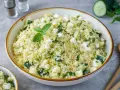 Frischer Couscous-Salat mit Gurkenwürfeln, Feta und Minze, garniert mit einer Minz-Dolde.