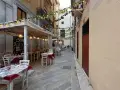Urocza uliczka w Trapani, gdzie zjeść? Stoliki restauracyjne pod girlandami z cytryn i lampek, idealne na wieczorny posiłek.