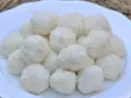 Un mucchio di dolci palline di cocco su un piatto bianco, perfette per una pausa golosa.
