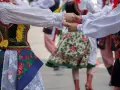 Tancerze w barwnych strojach ludowych, żywa muzyka folkowa w tle.