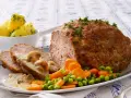 Herzhaftes Hackbraten-Mittagessen nach Omas Rezepten, serviert mit Salzkartoffeln, Pilzrahmsoße und Gemüse.