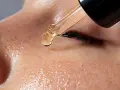 Goutte d'un sérum doré tombant sur une peau frecklée, essentielle à la routine soin visage matin et soir pour une peau éclatante.