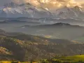 Złote światło oświetla najpiękniejsze szczyty w Polsce, Tatry, otoczone przez malownicze, zalesione wzgórza.