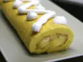 Un brazo de gitano amarillo con relleno cremoso y merengue blanco decorando la superficie.