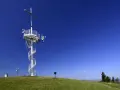 Wieża widokowa na górze Grzywackiej z krzyżem i spiralnymi schodami, na tle błękitnego nieba.