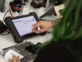 Mechanic uses a diagnostic tablet to connect to a car's ecm.