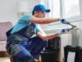 Tecnico con attrezzi effettua manutenzione termosifoni vicino a una finestra.